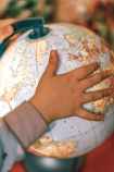 small kid spinning globe with physical map of world